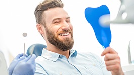 man smiling in dental mirror