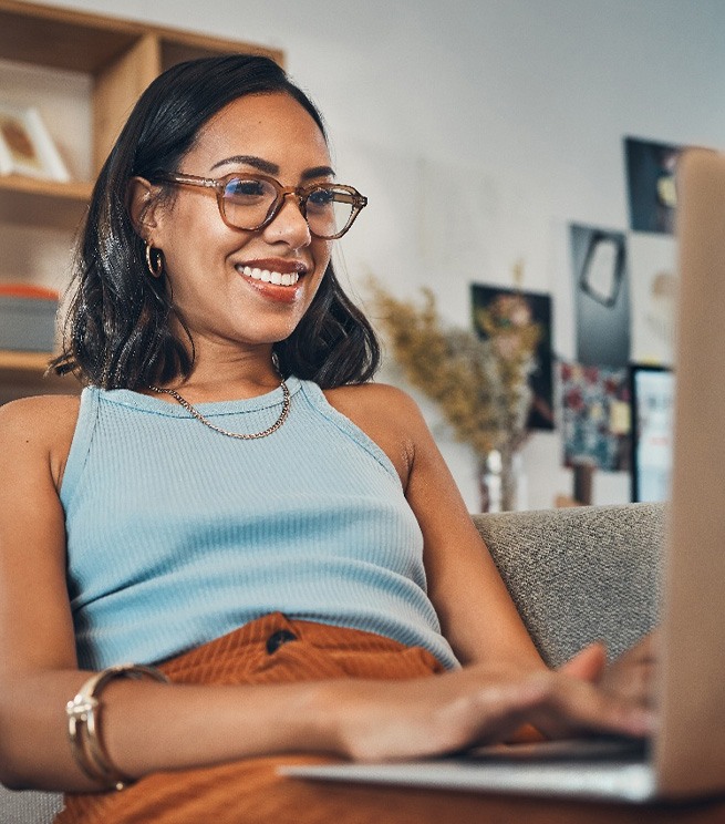 Woman smiling while working on laptop at home