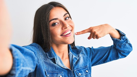 Smiling woman pointing to her white teeth