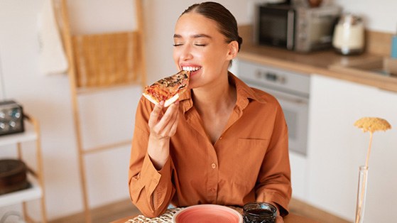 Woman enjoying meal in kitchen at home