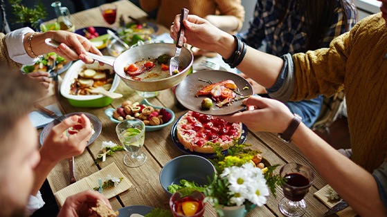 Hands of people enjoying a meal together at a table passing food to serve