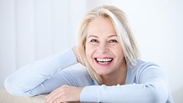 Smiling woman with dental implants in Wakefield on white background
