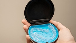 Patient holding Invisalign aligners in black and blue case