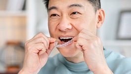 Smiling man placing Invisalign aligners on top teeth