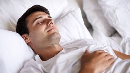 Man in white t-shirt, sleeping peacefully in bed
