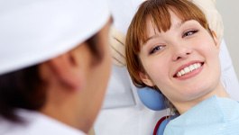 Red-haired woman sitting back and smiling at dentist