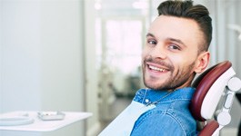 Man in denim jacket smiling in dental chair