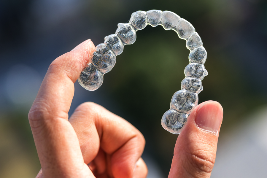 Someone holding up a clear aligner tray