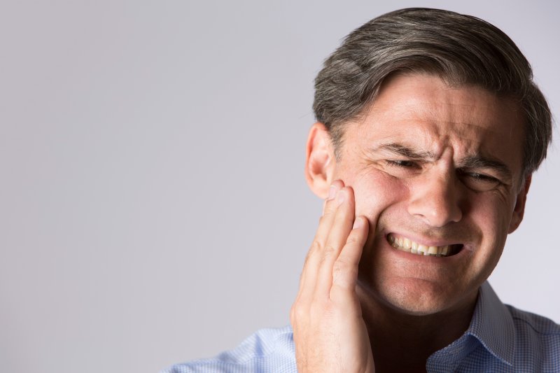 patient with dental emergency holding their cheek