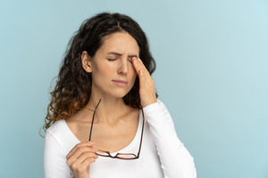 Woman taking off glasses, suffering from eye pain