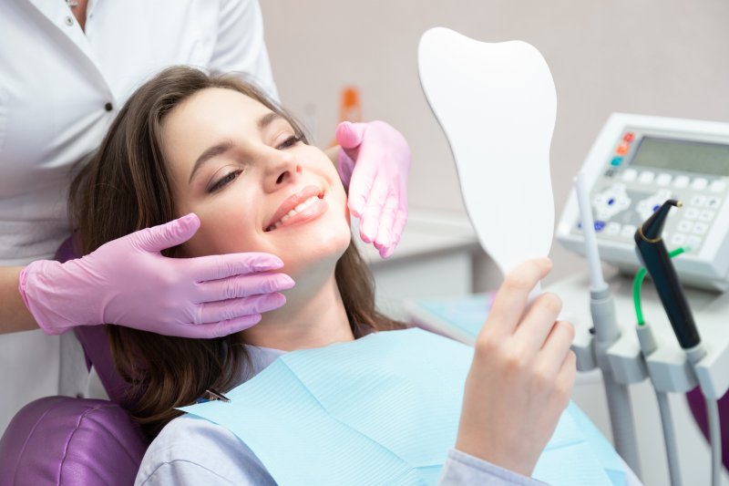 A woman admiring her smile after receiving cosmetic dentistry